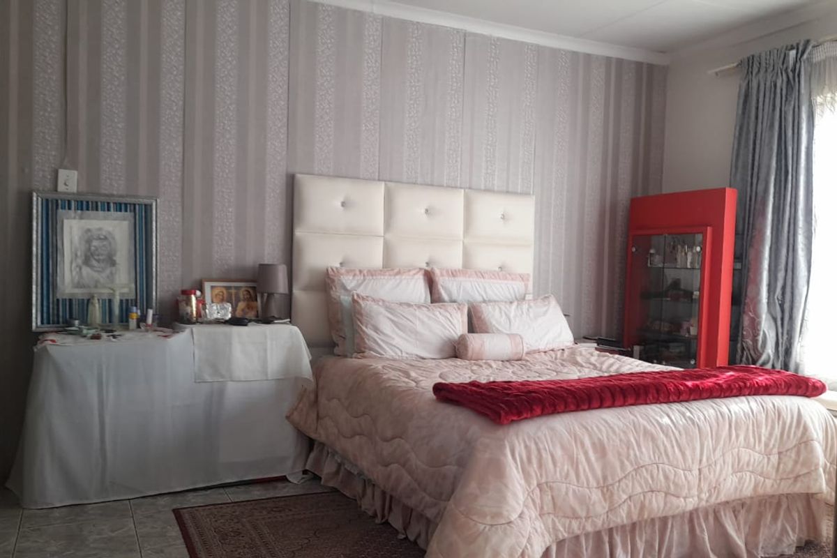 A bedroom featuring tiled flooring and decorative wallpaper, providing a functional space for rest.