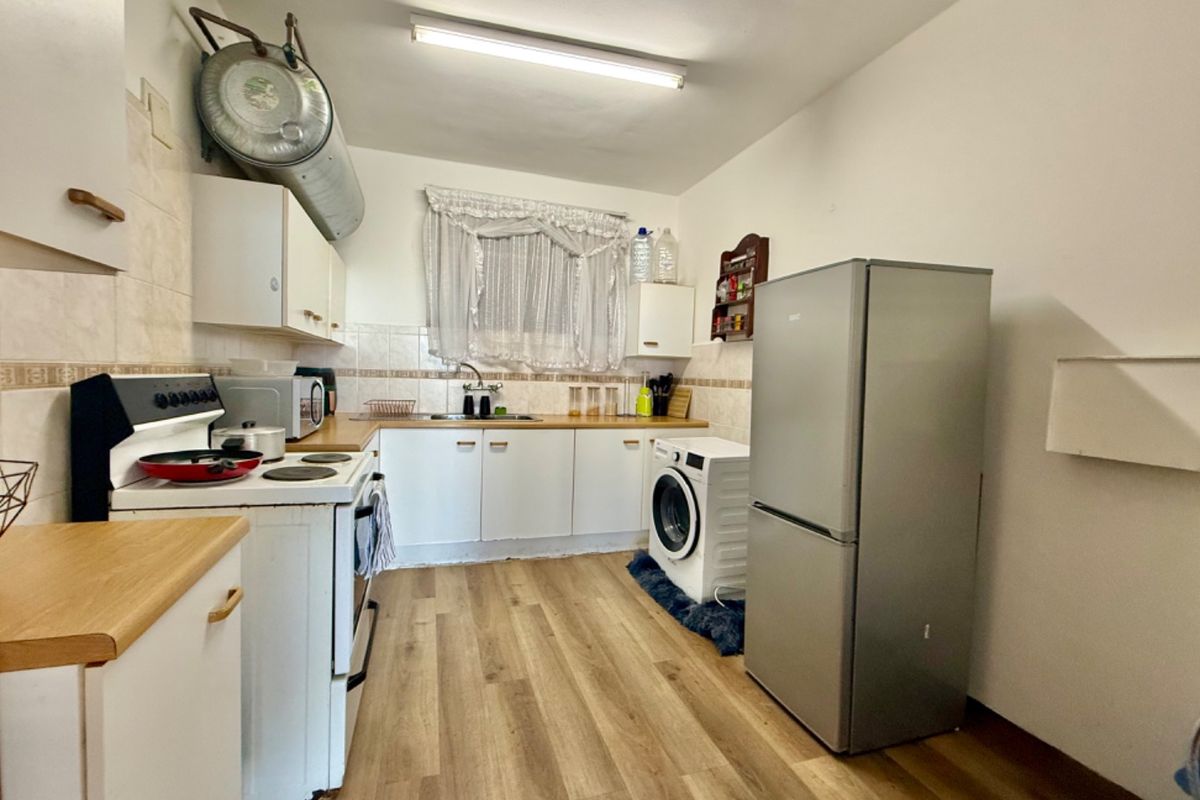 A functional kitchen featuring laminate countertops, built-in cabinetry, a tiled backsplash, and integrated stove, offering a practical layout for daily meal preparation.