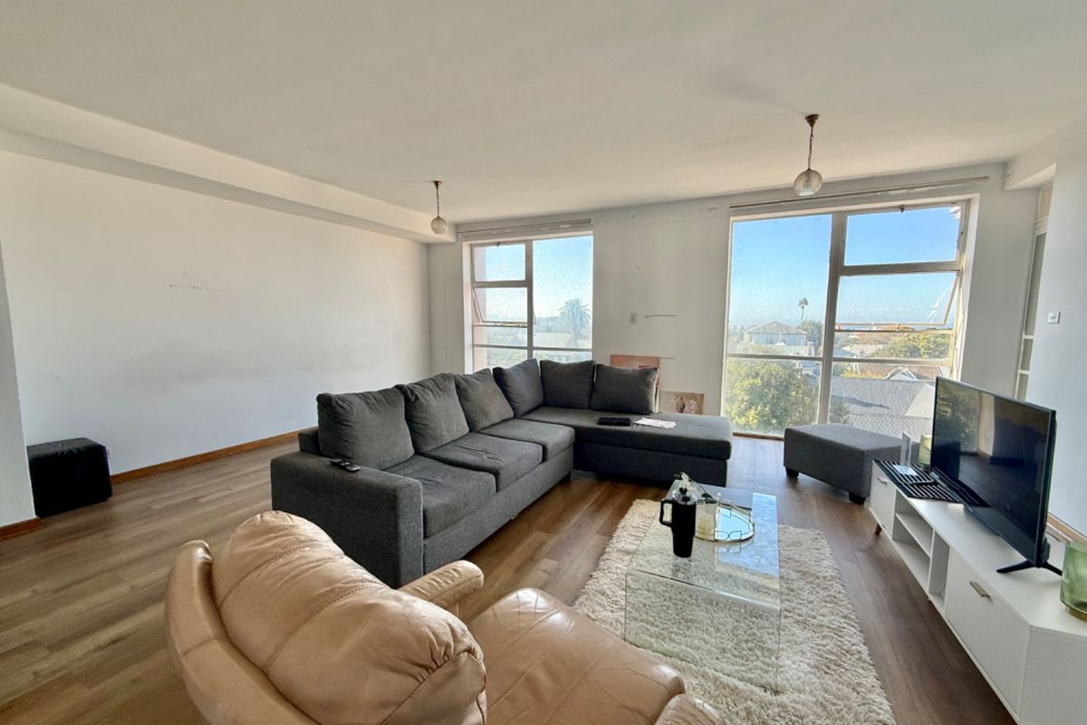 Spacious living room featuring laminate flooring and large windows that provide ample natural light and neighborhood views.