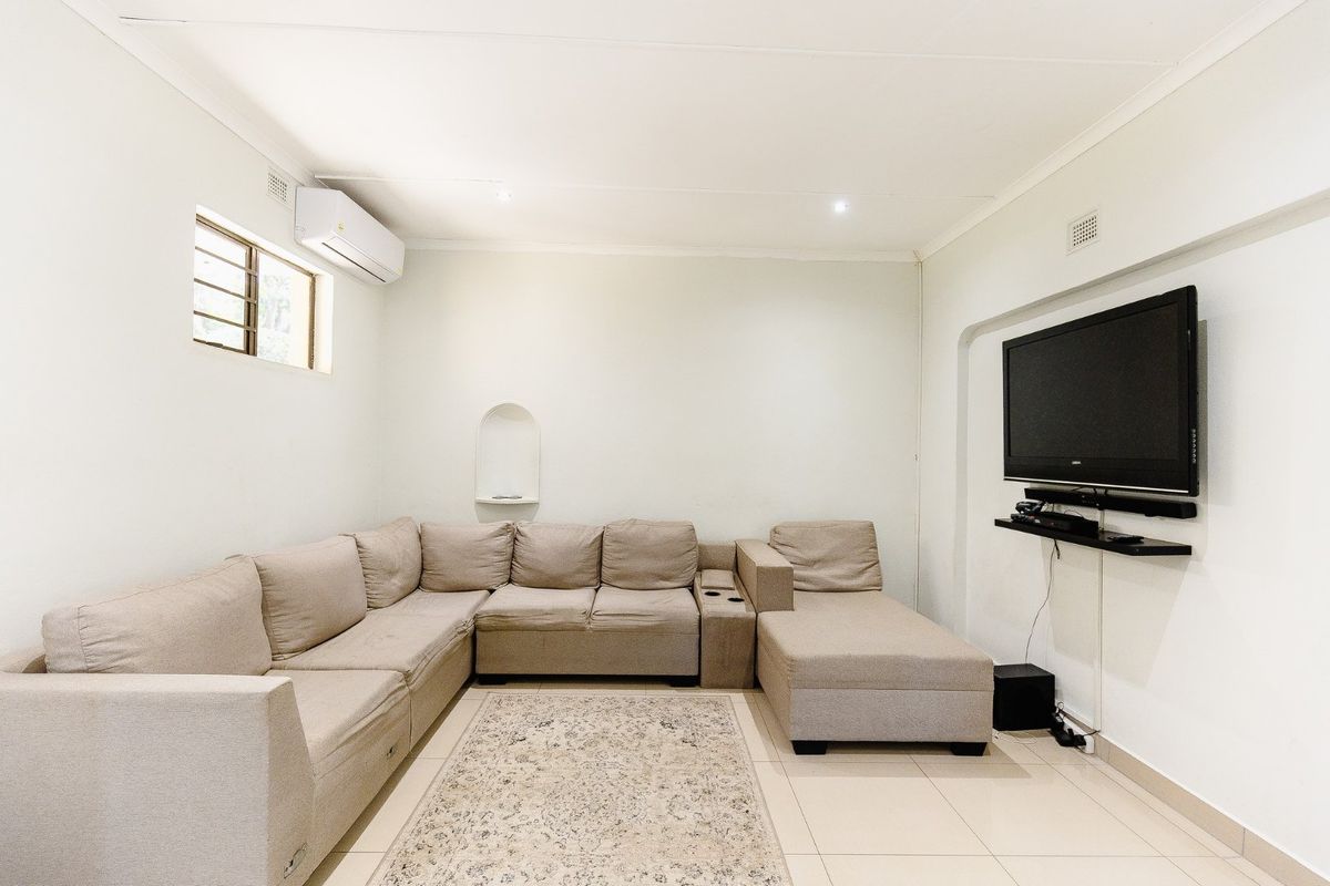 A functional living room featuring tiled flooring, a wall-mounted air conditioning unit, and a decorative recessed wall niche.