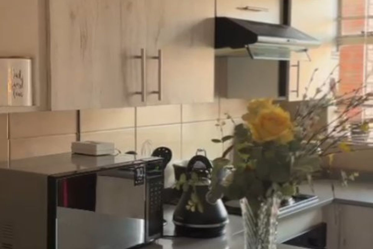 A functional kitchen featuring light wood-finish cabinetry, a tiled backsplash, and a stone countertop, providing a clean and practical workspace.