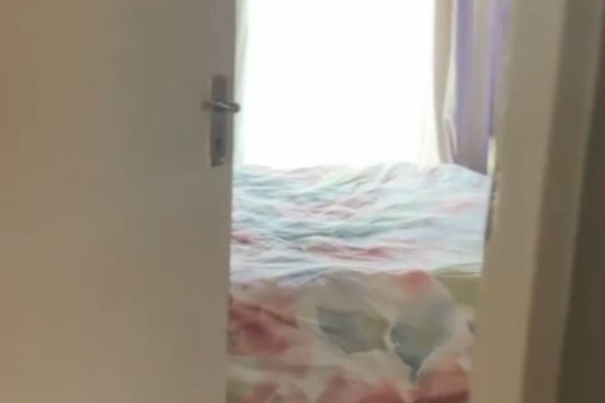A view into a bedroom featuring tiled flooring and a window, captured through a doorway.