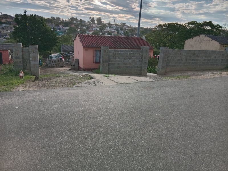Front view of a residential property featuring a tiled roof, security bars on windows, and an unfinished concrete block boundary wall.