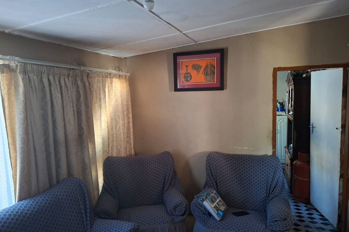 A living room area featuring standard wall finishes, curtain rails, and ceiling tiles, showing signs of wear and requiring cosmetic updates.