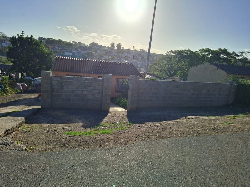 Front view of a residential property featuring a tiled roof and an unfinished concrete block boundary wall.