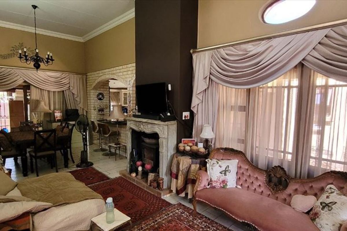 Spacious open-plan living area featuring a central fireplace, vaulted ceilings, and a distinctive brick archway leading to the dining space.