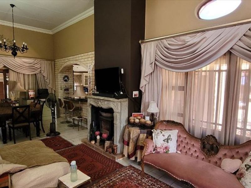 Spacious open-plan living area featuring a central fireplace, vaulted ceilings, and a distinctive brick archway leading to the dining space.