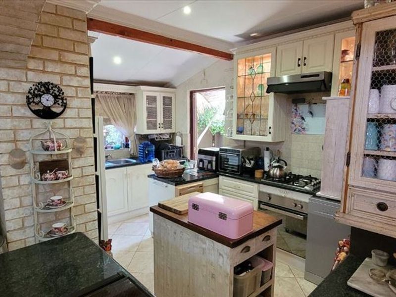 A rustic-style kitchen featuring built-in cabinetry, a gas hob with extractor, and an exposed brick feature pillar, offering a warm and functional cooking space.