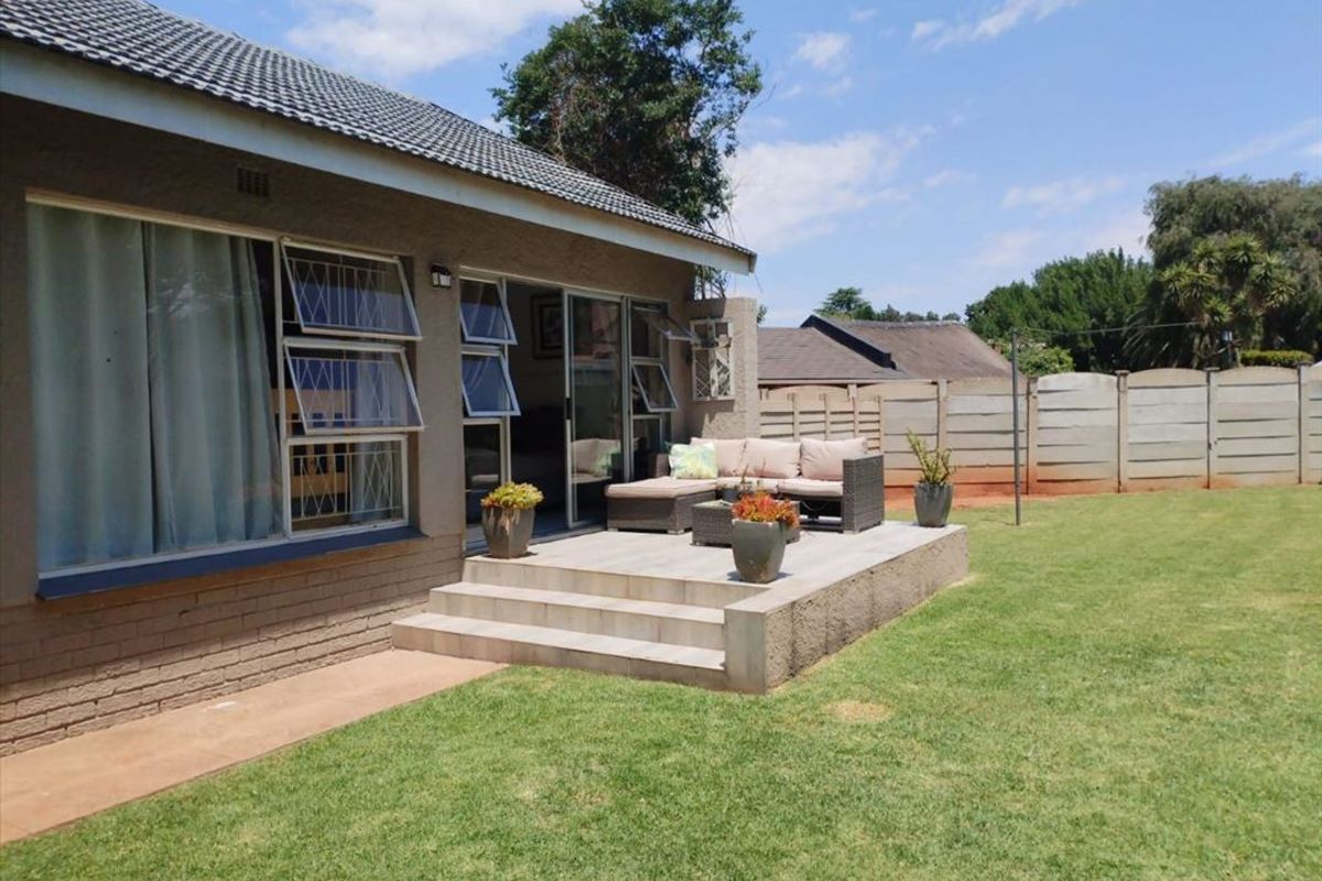 A well-maintained rear patio featuring tiled flooring and concrete steps, providing seamless access to the garden and lawn area.