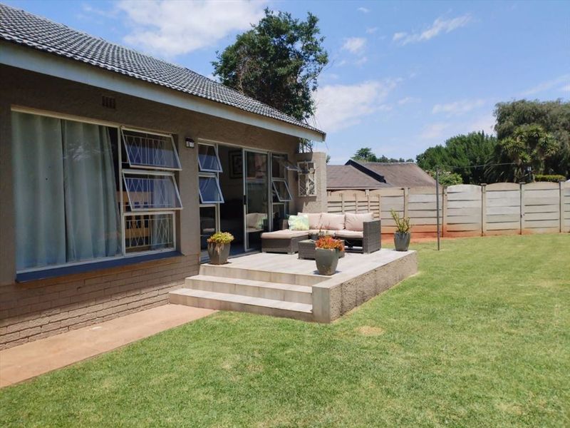 A well-maintained rear patio featuring tiled flooring and concrete steps, providing seamless access to the garden and lawn area.