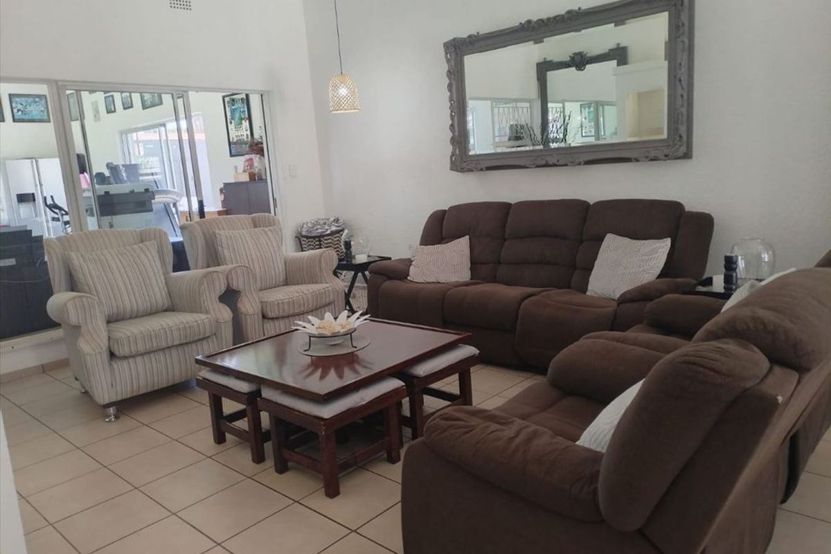 A spacious living room featuring neutral tiled flooring and a large sliding glass door providing access to an adjacent room.