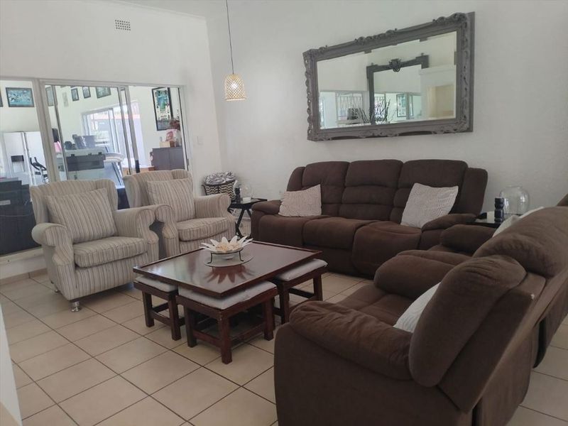 A spacious living room featuring neutral tiled flooring and a large sliding glass door providing access to an adjacent room.
