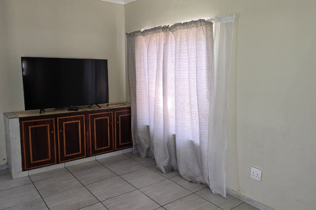 A living room area featuring tiled flooring and a built-in wooden cabinet unit.