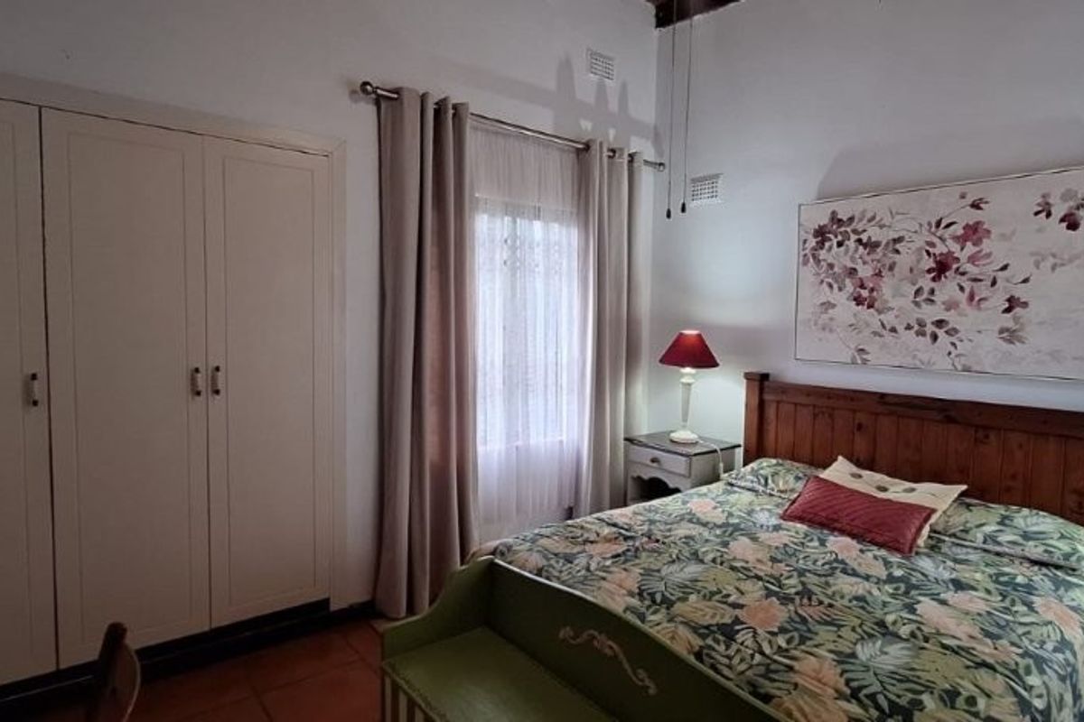 A bedroom featuring built-in cupboards, tiled flooring, and a ceiling fan, offering a functional and comfortable living space.