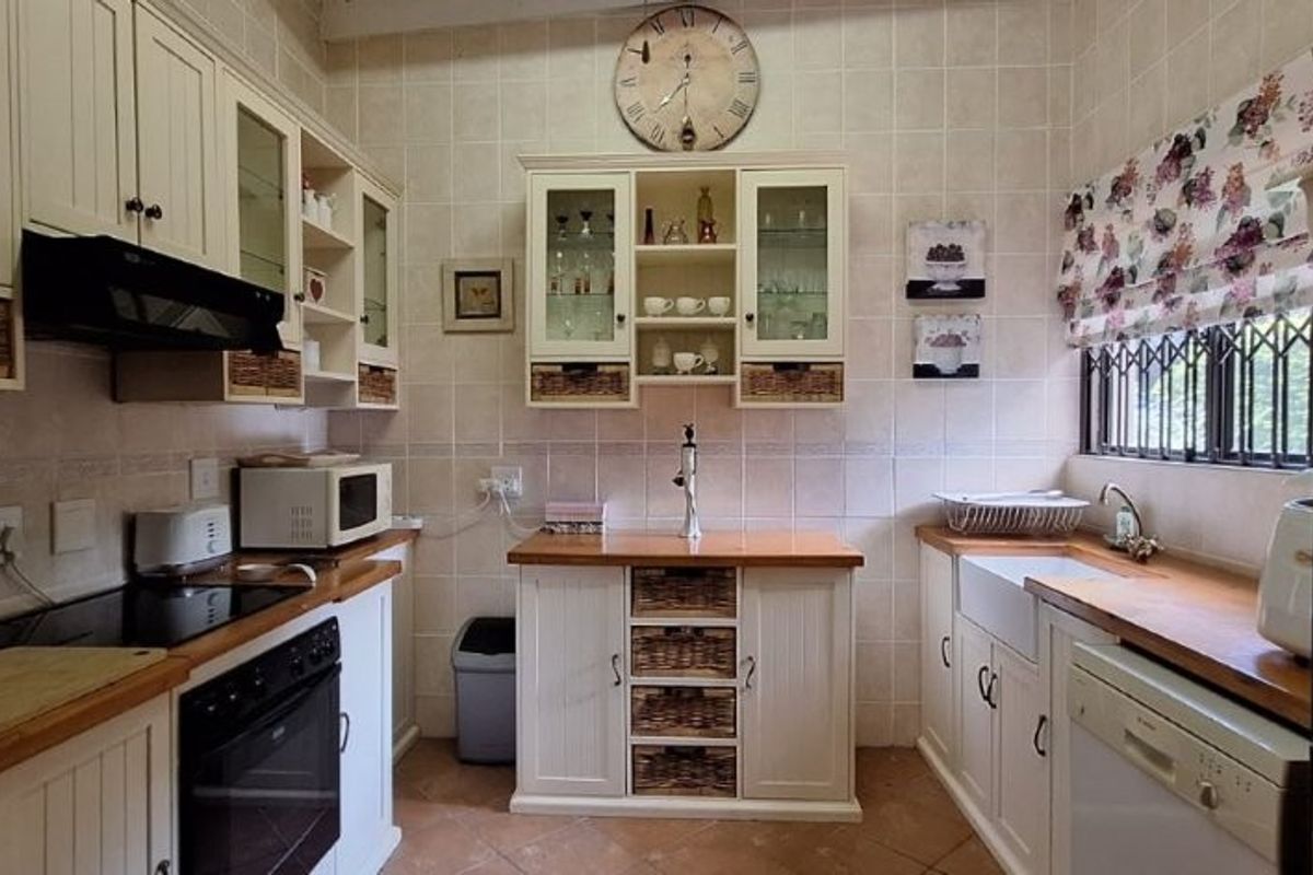 A charming country-style kitchen featuring timber countertops, farmhouse sink, built-in cabinetry, and integrated appliances, offering a warm and functional cooking space.