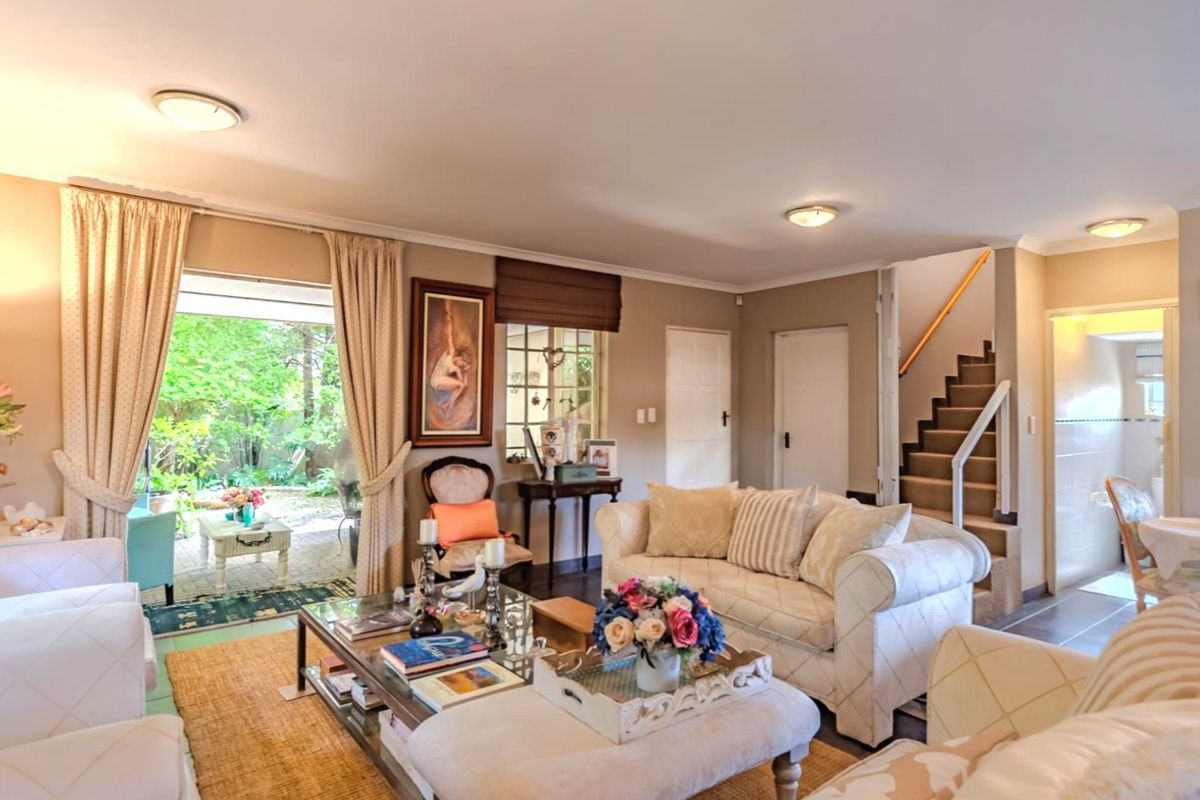 Spacious living room featuring a staircase, neutral wall finishes, and direct access to a private garden patio through sliding glass doors.