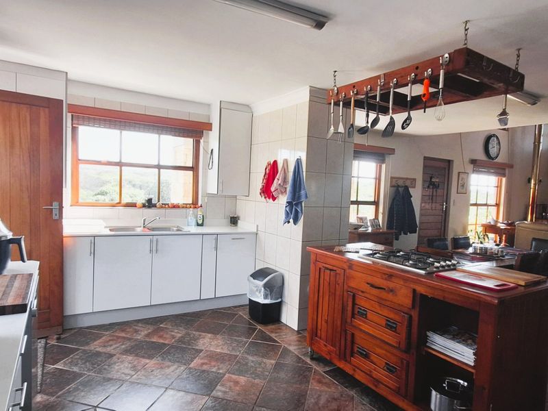 Open-plan kitchen and living area featuring a wooden island with gas hob, tiled flooring, and a cozy wood-burning fireplace in the adjacent lounge.