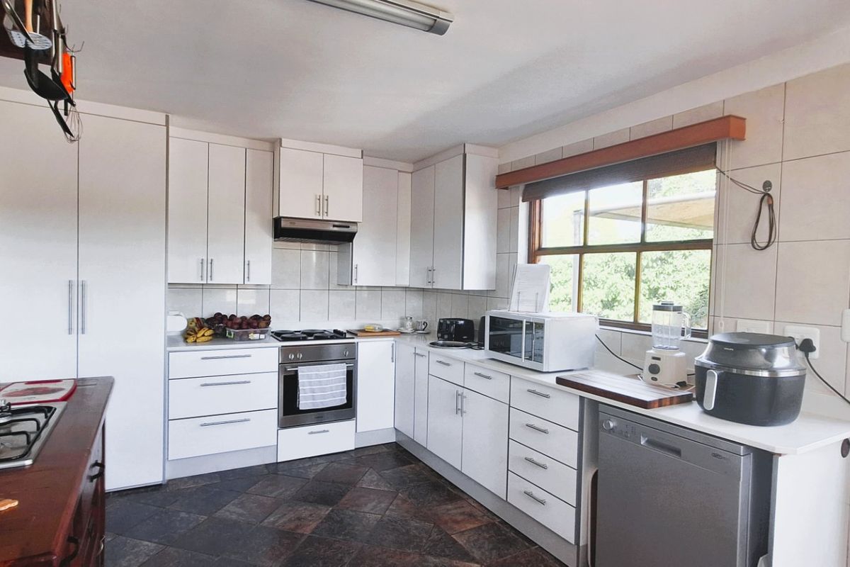 A functional kitchen featuring white cabinetry, stone countertops, a gas hob, and tiled flooring, offering a clean and practical workspace.