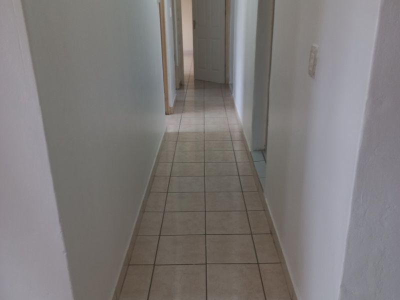 A clean, empty hallway featuring neutral ceramic floor tiles and multiple internal doorways providing access to adjacent rooms.