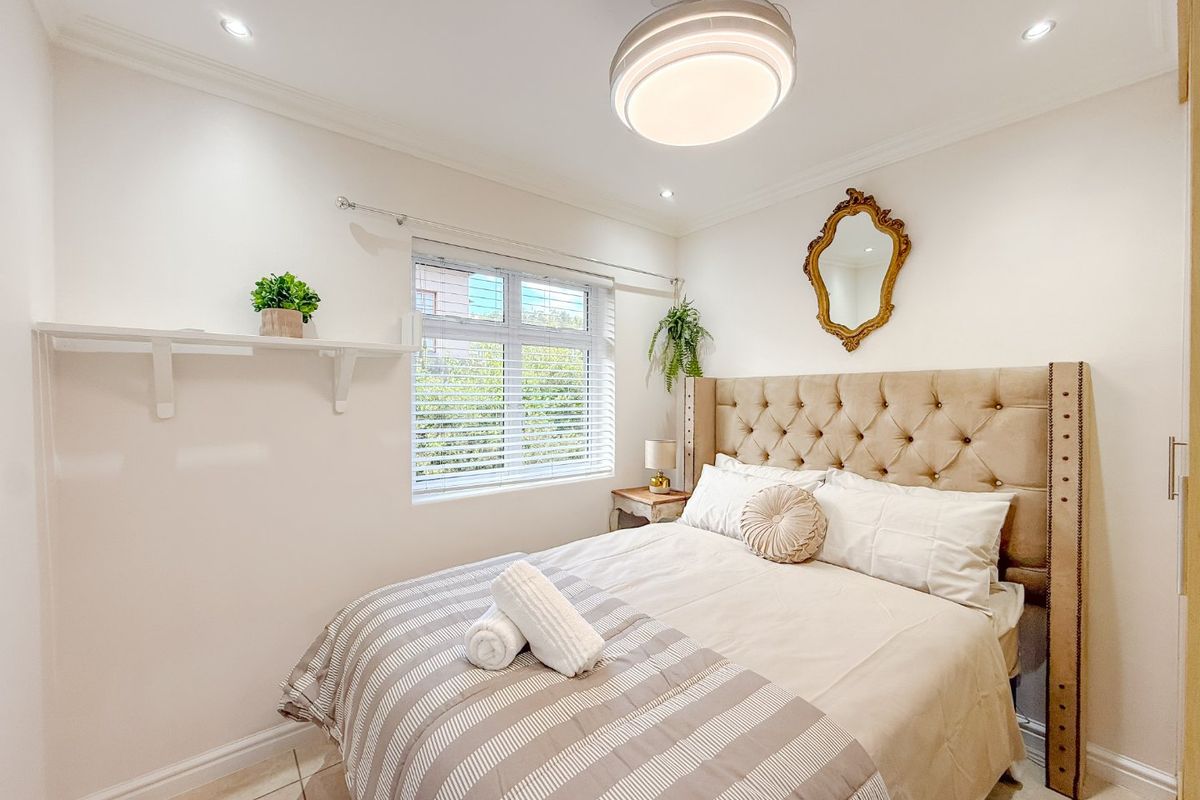 A well-maintained bedroom featuring tiled flooring, recessed downlights, a ceiling fan, and built-in shelving, offering a clean and functional living space.