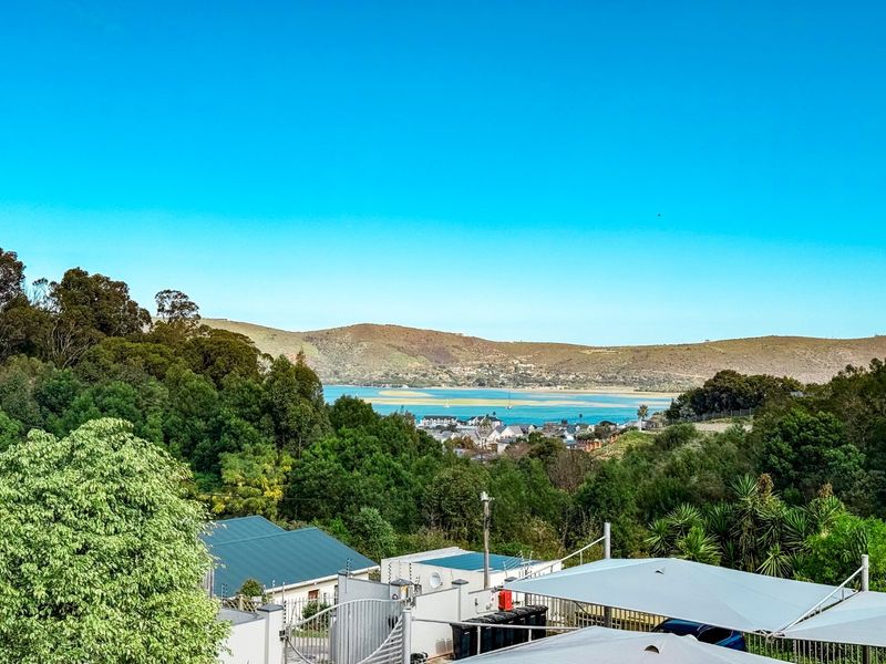 A scenic elevated view overlooking a coastal lagoon, surrounding hills, and residential neighborhood.