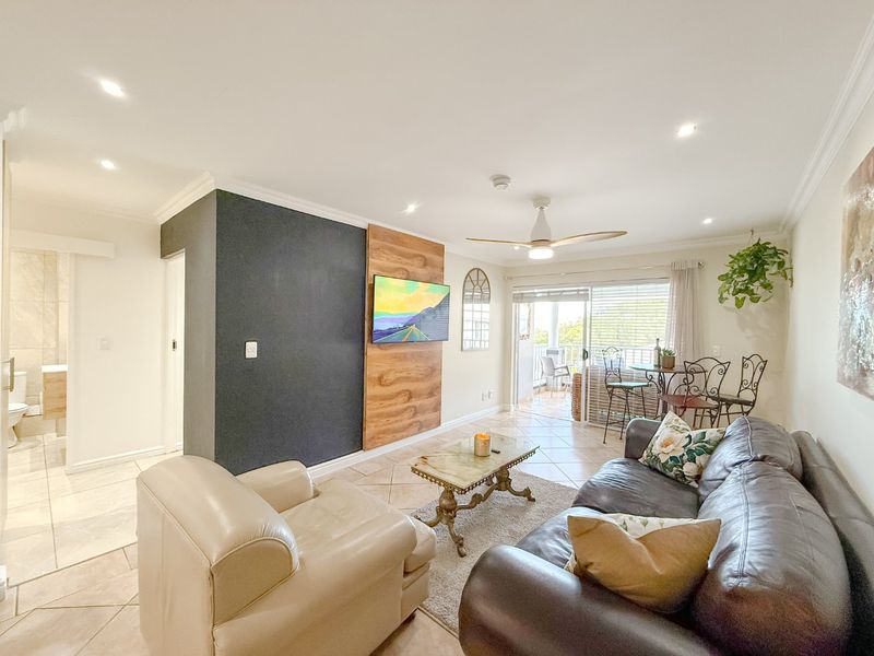 Bright and spacious living area featuring tiled floors, recessed lighting, a ceiling fan, and direct access to a private balcony through sliding glass doors.