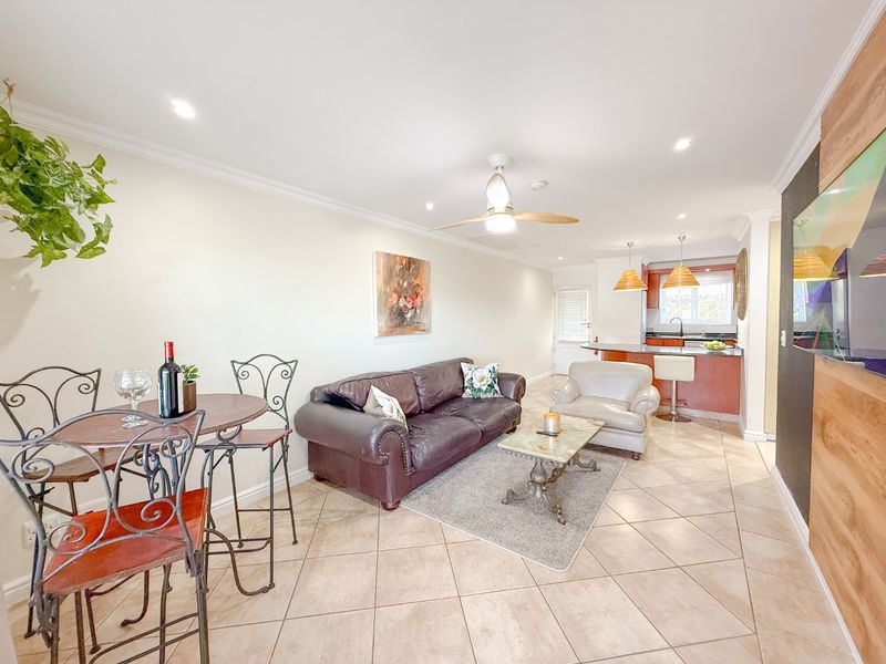 An open-plan living and kitchen area featuring ceramic tile flooring, recessed lighting, a ceiling fan, and a functional kitchen island with pendant lights.