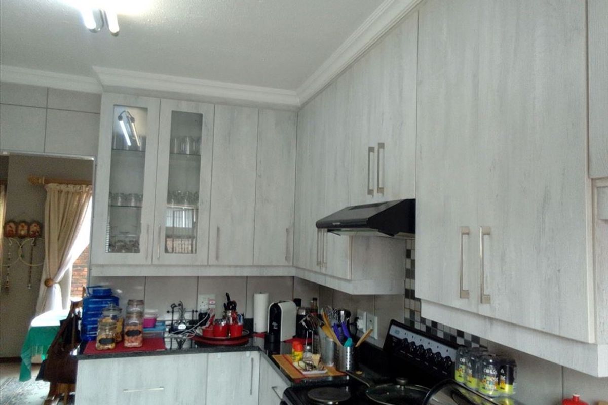 A functional kitchen featuring light wood-grain cabinetry, a tiled backsplash, and built-in cooking appliances, offering a practical layout for daily meal preparation.