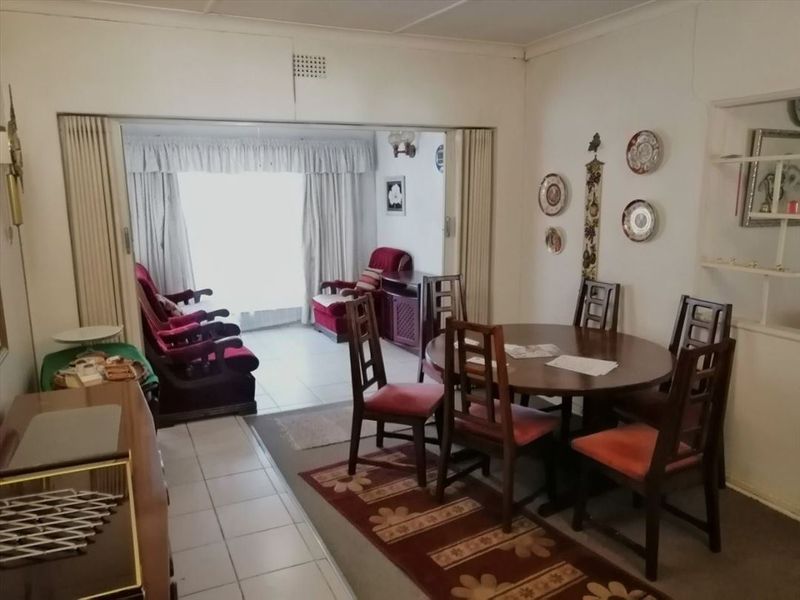 Open plan living and dining area featuring tiled flooring and a folding room divider connecting to an adjacent lounge space.