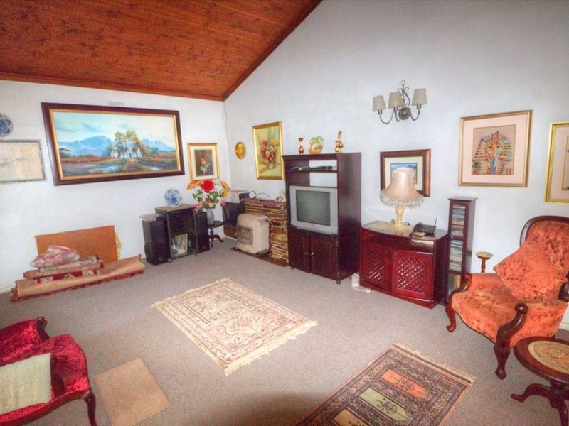 A living room featuring a high vaulted timber ceiling and neutral wall finishes, offering a spacious area for relaxation.