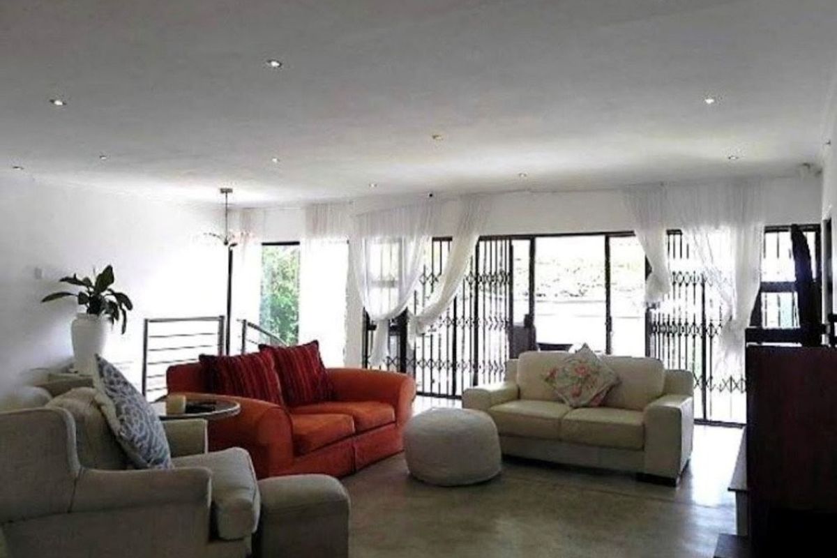 Spacious living room featuring polished concrete floors, recessed lighting, and large sliding glass doors with security gates leading to the exterior.