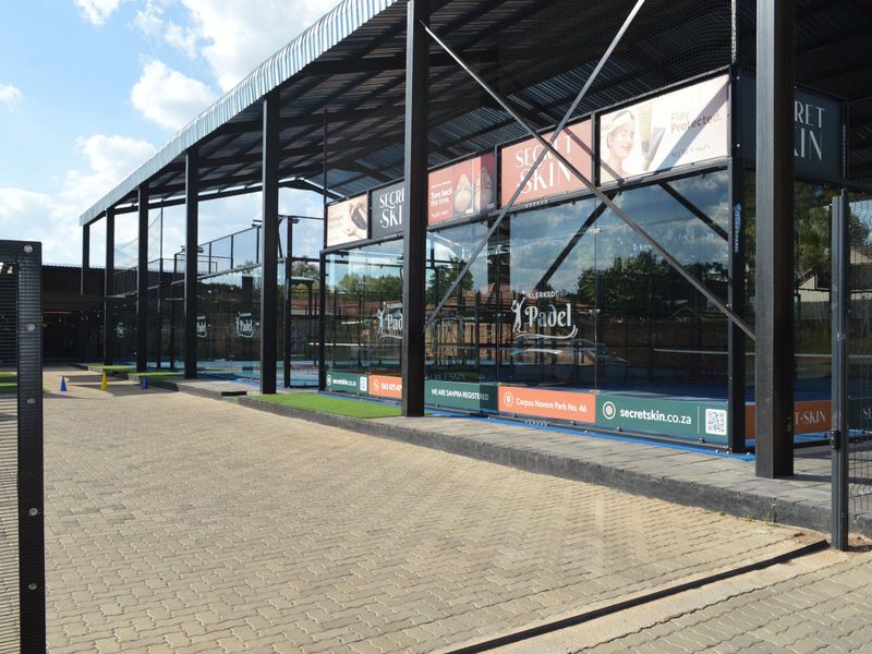 Modern commercial padel court facility featuring high-quality glass enclosures, steel structural framing, and paved exterior access.