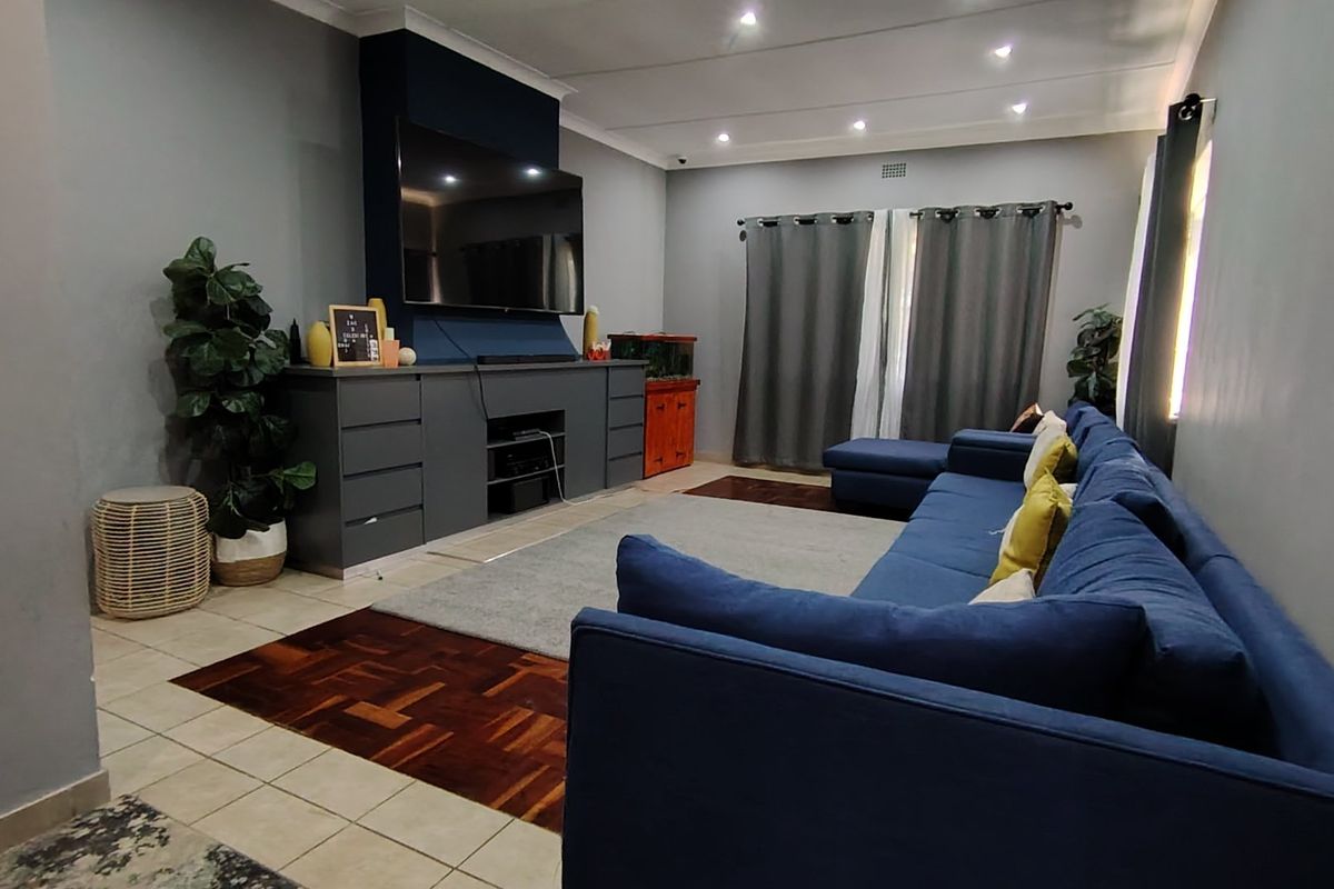 Spacious living room featuring a combination of parquet and tiled flooring, recessed downlighting, and a custom built-in media console.