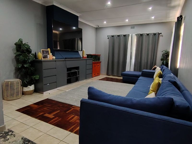 Spacious living room featuring a combination of parquet and tiled flooring, recessed downlighting, and a custom built-in media console.
