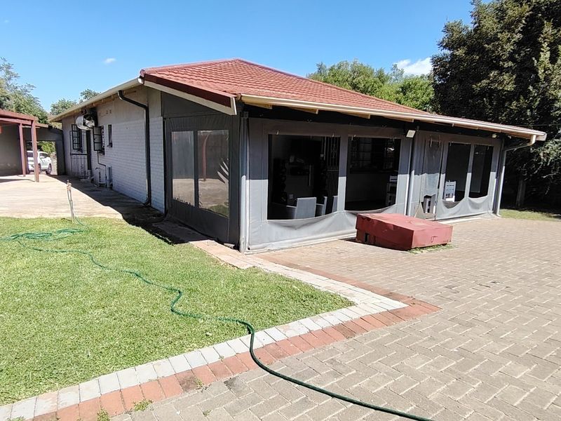 Rear view of the property featuring a paved patio area, enclosed outdoor space, and a well-maintained lawn.