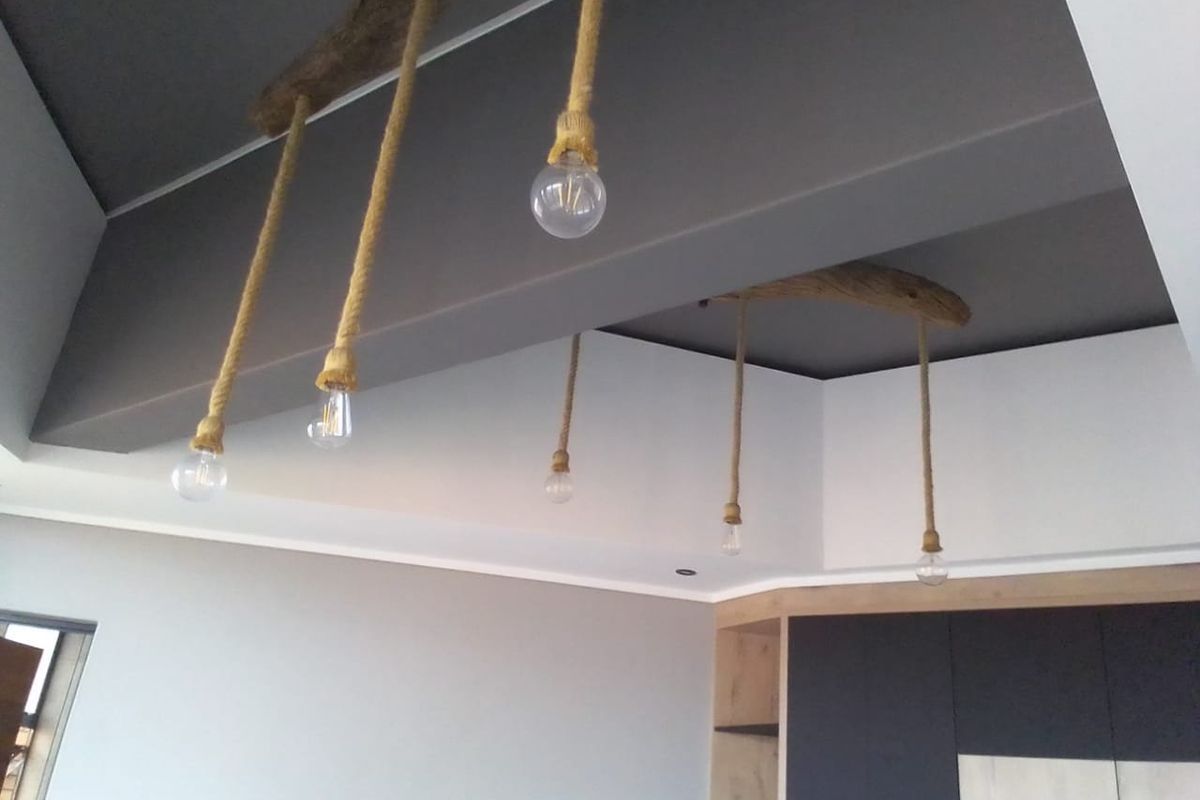 A modern living area featuring a recessed ceiling with decorative rope pendant lighting and built-in cabinetry.