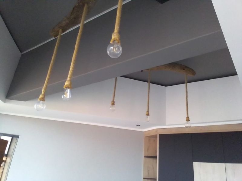 A modern living area featuring a recessed ceiling with decorative rope pendant lighting and built-in cabinetry.