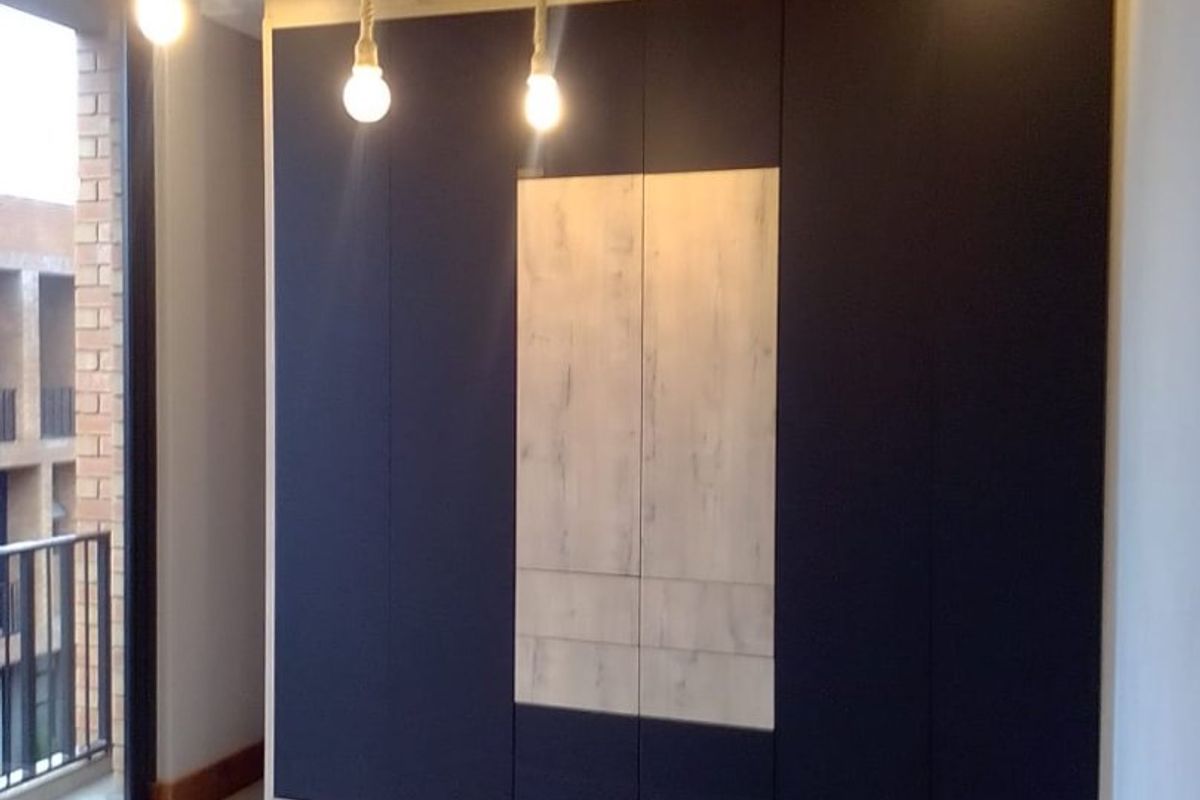 Modern bedroom featuring sleek built-in cupboards with contrasting wood-look panels, tiled flooring, and access to a private balcony.