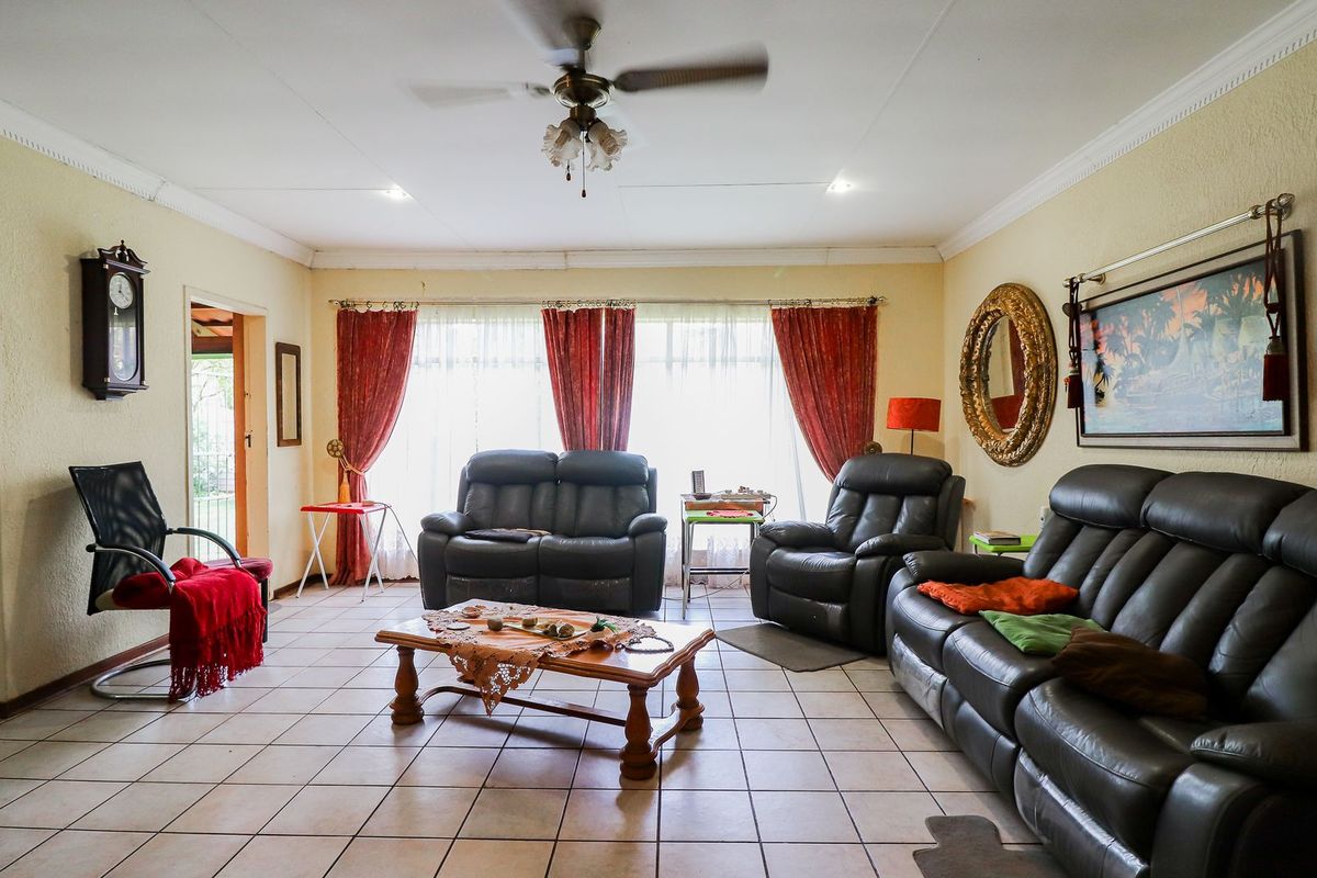 A spacious living room featuring tiled flooring, a ceiling fan, and a wall-mounted gas heater, offering a comfortable and functional living space.