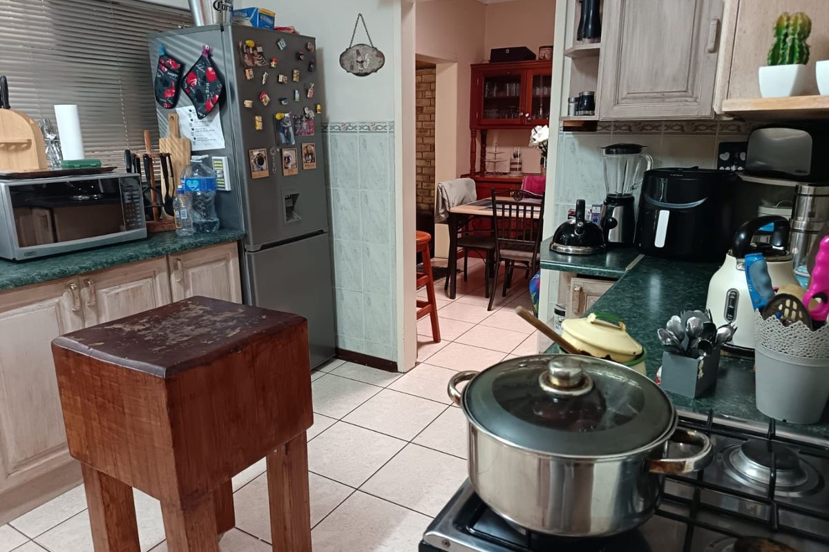 A functional kitchen featuring tiled flooring, a gas hob, and built-in cabinetry with a view through to the adjacent dining area.