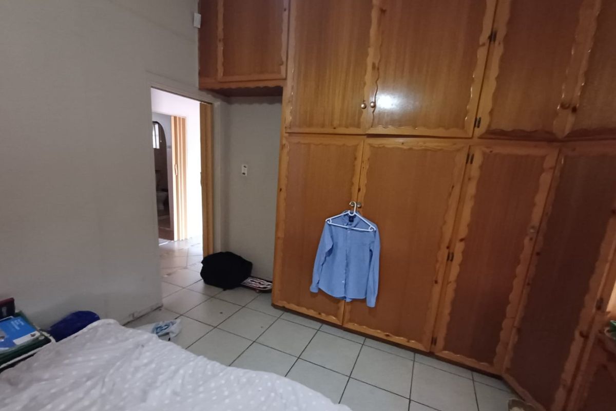 A bedroom featuring extensive built-in wooden cabinetry and tiled flooring, offering potential for modernization and aesthetic updates.