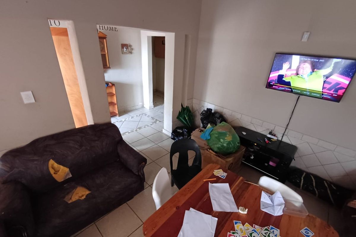 A living area featuring tiled flooring and wall-mounted television setup, requiring cosmetic updates to improve the overall aesthetic and condition of the space.