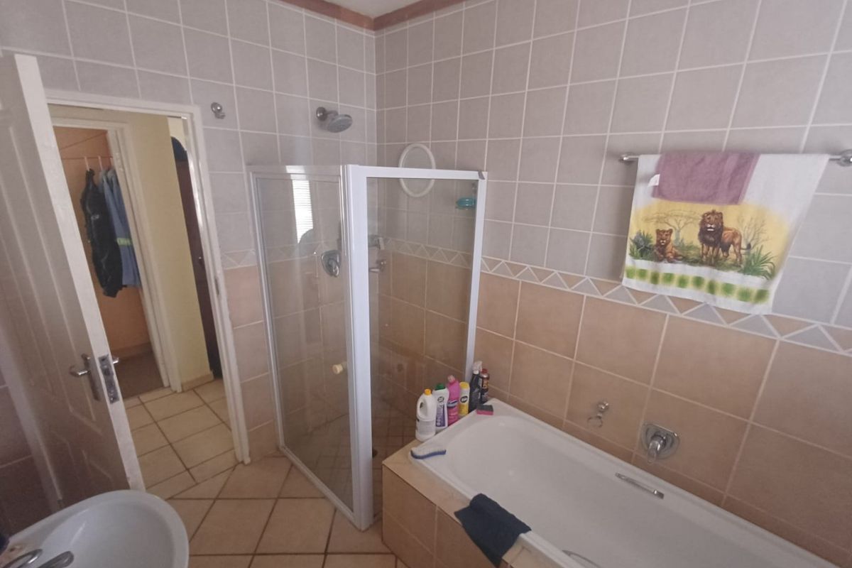 A functional bathroom featuring a built-in bathtub, a separate glass-enclosed shower, and tiled flooring with wall-mounted fixtures.