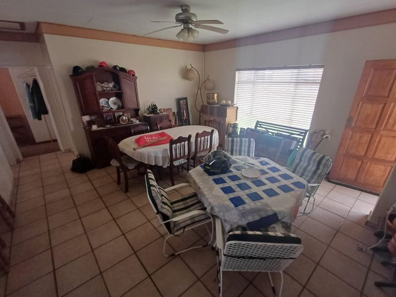 A dining area featuring tiled flooring, a ceiling fan, and natural light from a window with fitted blinds.