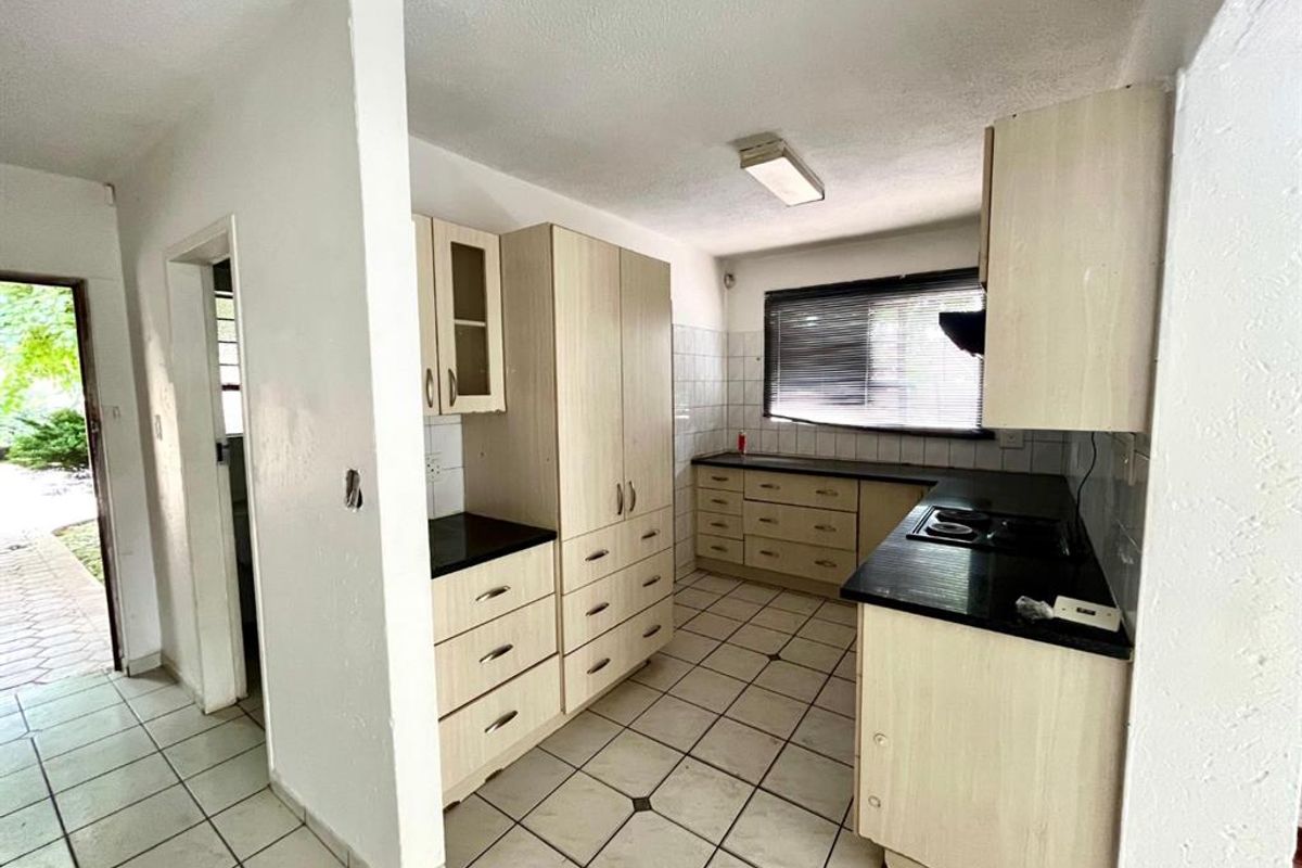 A functional kitchen featuring built-in cabinetry, laminate countertops, and tiled flooring, offering a blank canvas for potential modern updates and renovation.