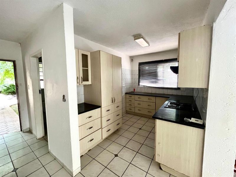 A functional kitchen featuring built-in cabinetry, laminate countertops, and tiled flooring, offering a blank canvas for potential modern updates and renovation.
