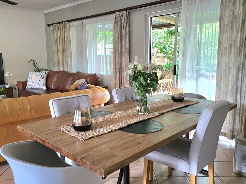 Open-plan living and dining area featuring tiled flooring, a ceiling fan, and large sliding glass doors providing access to the outdoor space.