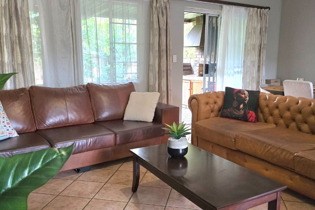 A comfortable living room featuring tiled flooring, large windows for natural light, and direct access to an outdoor patio area.