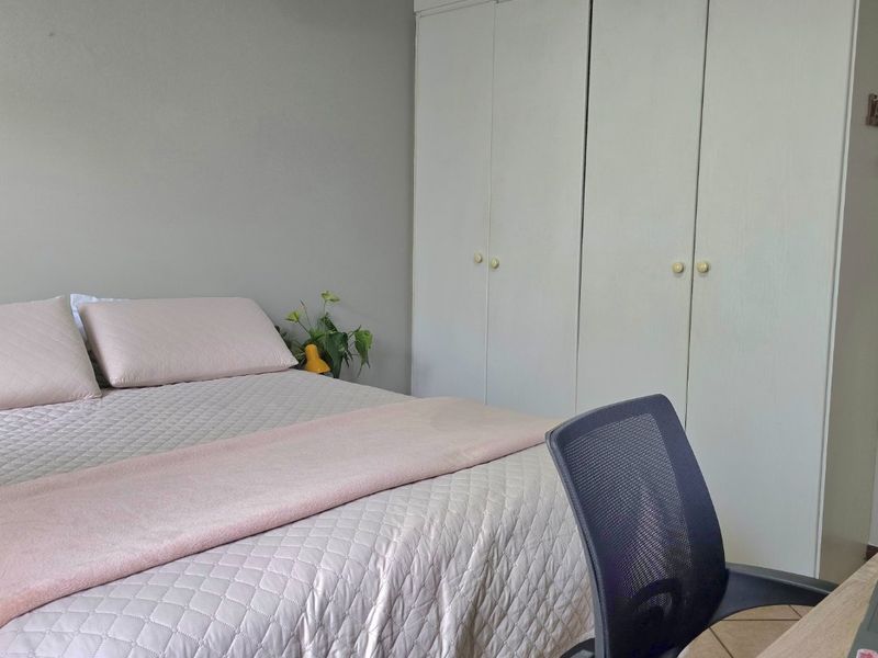 A functional bedroom featuring neutral wall tones and practical built-in cupboard storage.