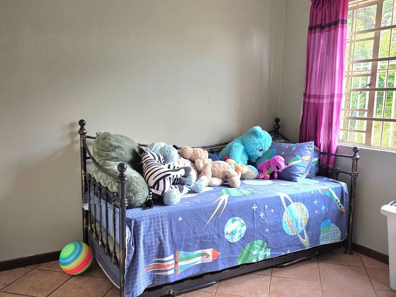 A bedroom featuring tiled flooring and a window fitted with security bars, providing natural light.